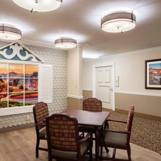 A neatly arranged room with a table and four chairs, decorated with artwork on the walls and elegant lighting fixtures.
