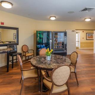 A cozy room with a round table and chairs, featuring vending machines and floral decor.