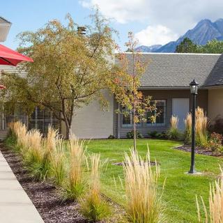 A scenic view of buildings with a well-maintained lawn and mountains in the background.