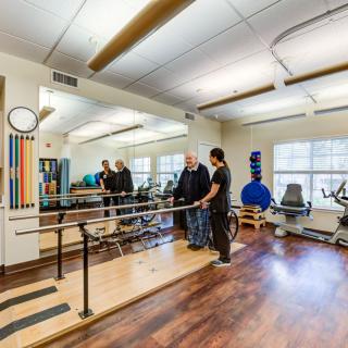 A physical therapy session taking place in a healthcare facility with various exercise equipment.
