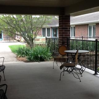A covered patio area with a table and chairs overlooking a garden.
