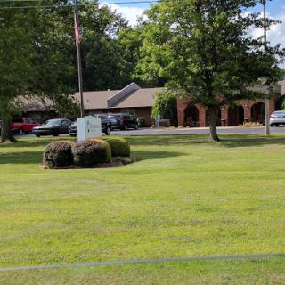 A peaceful view of a building surrounded by well-maintained lawns and trees.