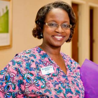A smiling healthcare professional in a colorful uniform indoors.