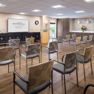 A modern conference room set up with chairs facing a projector screen, ready for a lecture or presentation.