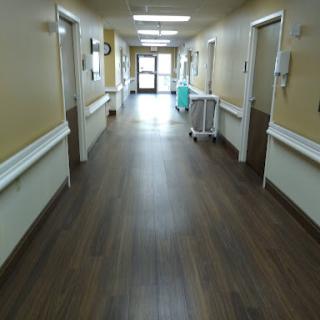 A long, empty corridor in a hospital, leading to the exit.