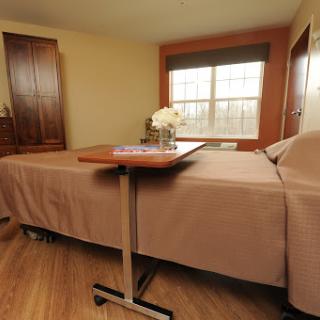A cozy and well-lit bedroom featuring a neatly made bed, a small table, and decorative flowers.