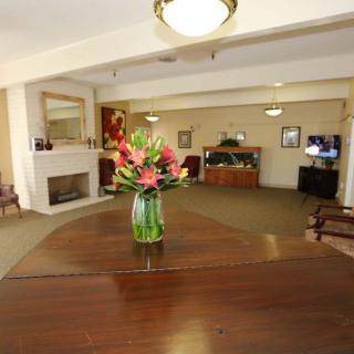 A cozy living room featuring a wooden table with a vase of flowers and a fireplace in the background.