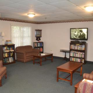 A cozy living room with comfortable seating, a television, and bookshelves.