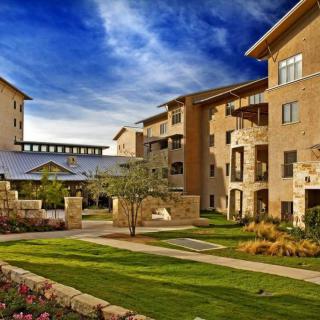 A view of modern residential apartment buildings with well-maintained gardens and a clear blue sky.