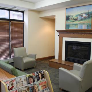 A cozy waiting area featuring comfortable chairs, a fireplace, and magazines.