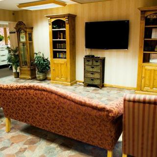 A cozy living room with a sofa, television, and wooden cabinets.