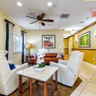 A cozy living room with comfortable seating, wall art, and a ceiling fan.