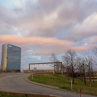 A modern building stands tall against a backdrop of colorful clouds and a winding road.