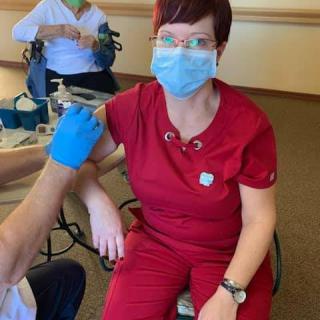 A healthcare worker receiving a COVID-19 vaccine while wearing a mask.