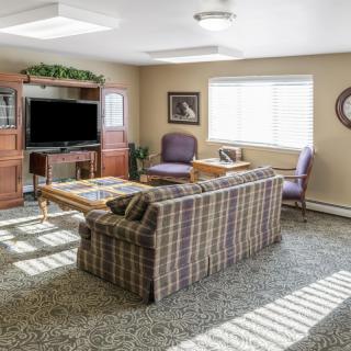 A cozy living room with a sofa, chairs, and a television.
