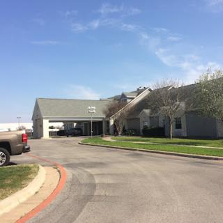 A view of a residential building with a parking area under a clear blue sky.
