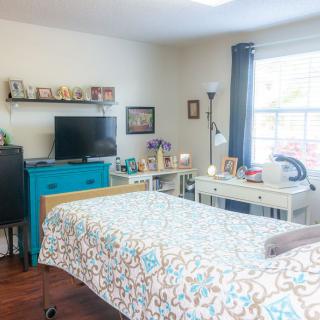 A cozy bedroom with a bed, dresser, and television.