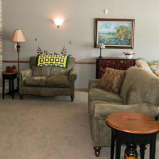 A cozy living room with a sofa, armchair, and various pieces of furniture.