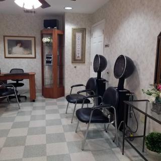 A cozy salon interior featuring chairs, hair dryers, and a desk with art on the walls.
