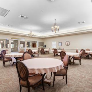 A spacious dining area featuring round tables and upholstered chairs, designed for gatherings.