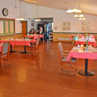 An empty dining hall with tables and chairs neatly arranged, ready for guests.