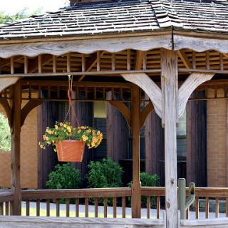 A charming gazebo featuring a hanging flower planter, surrounded by greenery.