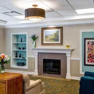 A cozy living room with a fireplace, comfortable seating, and decorative artwork.