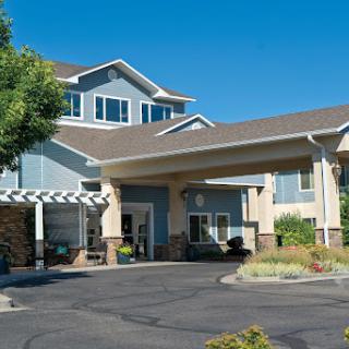A welcoming hotel entrance surrounded by greenery under a clear blue sky.
