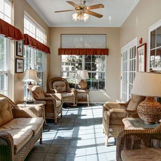 A cozy sunroom filled with natural light, featuring comfortable seating and stylish decor.