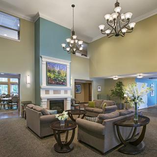 A modern living room with comfortable seating, elegant chandeliers, and a fireplace, complemented by tasteful artwork.