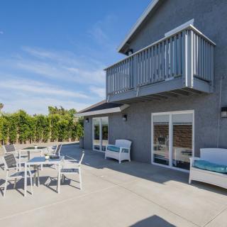 A sunny backyard patio with modern outdoor furniture and a balcony.