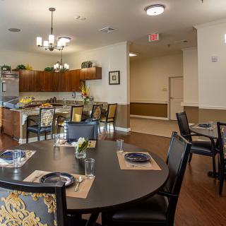 A well-arranged dining area with set tables and a view of a kitchen in the background.