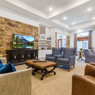 A modern living room with comfortable seating, a large television, and a stone accent wall.