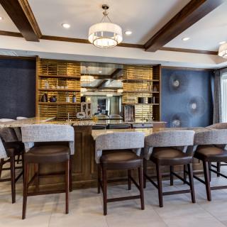 A stylish home bar with modern decor and ample seating, featuring elegant lighting and a well-organized wine display.