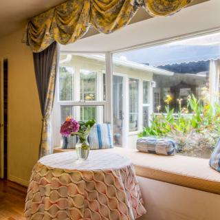 A cozy living room with a large window, floral arrangements on the table, and elegant curtains.