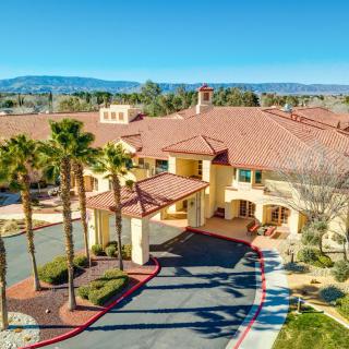 Aerial view of a large building surrounded by palm trees with mountains in the background.