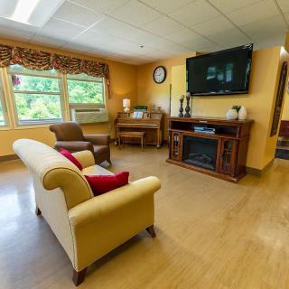 A cozy living room with a sofa, chairs, television, and large windows.