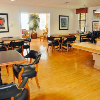 A cozy restaurant dining area with wooden floors, tables, and chairs.