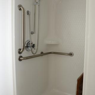 Accessible shower with grab bars and a white interior.