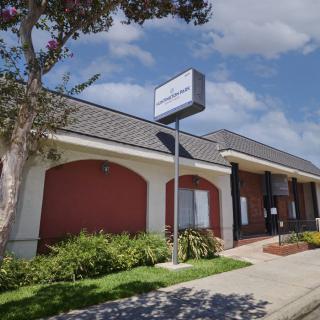 A commercial building with a brick facade and prominent signage, surrounded by landscaped greenery.