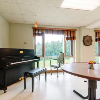 A peaceful music room with a piano and large windows offering a scenic view.