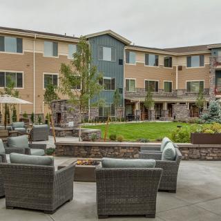 A modern apartment complex with outdoor seating and landscaped garden area.