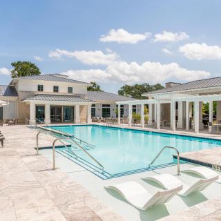 A luxurious outdoor swimming pool area with modern architecture on a sunny day.