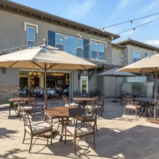 A sunny outdoor patio area with tables, chairs, and large umbrellas at a restaurant.