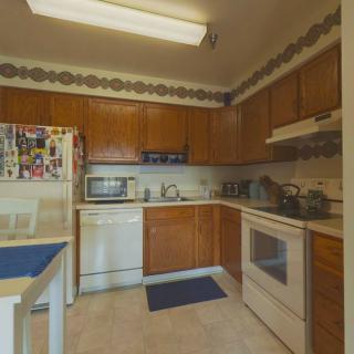 A cozy kitchen with wooden cabinets, featuring modern appliances including a refrigerator, microwave, oven, and dishwasher.