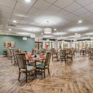 Spacious dining area with neatly arranged tables and chairs, featuring wooden flooring and elegant decor.