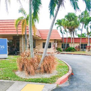 A well-maintained building surrounded by lush palm trees and landscaping.