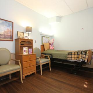 A cozy hospital room featuring a bed, two chairs, and personal touches.