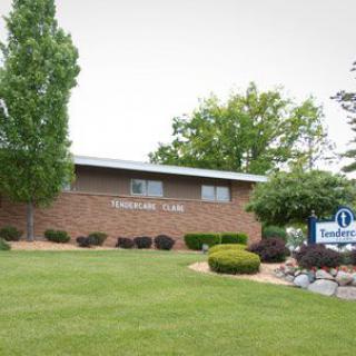 A small brick office building with well-maintained landscaping and a sign in front.