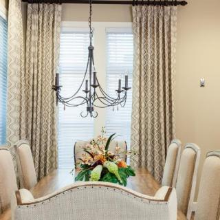 A elegantly decorated dining room with a chandelier, curtains, and floral centerpiece.